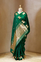 A green Banarasi silk saree with gold zari border for Navratri, Diwali, Durga Puja, and weddings, displayed on a mannequin.