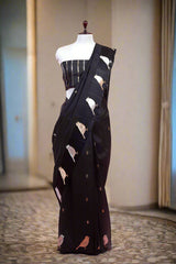 Black saree with bird patterns on a mannequin against a pink background
