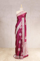 Magenta saree with white patterns on a mannequin against a light gray background