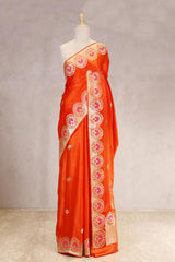 Orange saree with intricate patterns on a mannequin against a plain background