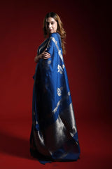 Woman wearing a blue saree with white patterns on a red background