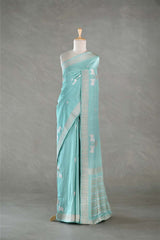 Light blue saree with white patterns on a mannequin against a gray background