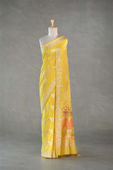 Yellow saree with floral patterns on a mannequin against a gray background
