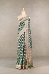 Bottle Green Banarasi silk saree with silver-gold intricate woven patterns draped on a mannequin against a gray background