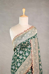 Bottle Green Banarasi silk saree with silver-gold intricate woven patterns draped on a mannequin against a gray background