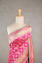 Pink Banarasi silk saree with light gold intricate peacock and elephant woven patterns draped on a mannequin against a gray background