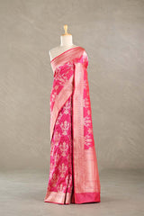 Pink Banarasi silk saree with light gold floral woven patterns draped on a mannequin against a gray background