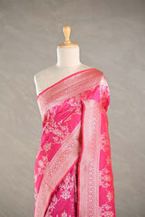 Pink Banarasi silk saree with light gold floral woven patterns draped on a mannequin against a gray background