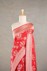 Red Banarasi silk saree with light gold floral woven patterns draped on a mannequin against a gray background