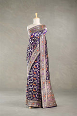 Red Banarasi silk saree with light gold intricate Pichwai woven patterns draped on a mannequin against a gray background