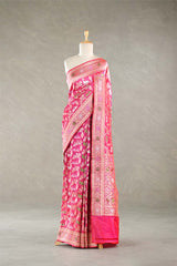 Pink Banarasi silk saree with light gold intricate Pichwai woven patterns draped on a mannequin against a gray background