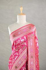 Pink Banarasi silk saree with light gold intricate Pichwai woven patterns draped on a mannequin against a gray background