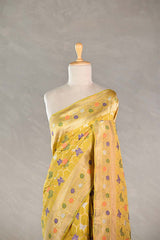 Yellow Banarasi silk saree with multicolor floral patterns draped on a mannequin against a neutral background