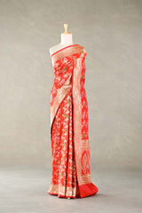 Red Banarasi silk saree with floral patterns on a mannequin against a plain background