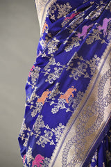 Blue saree with intricate gold and pink patterns on a gray background
