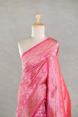 Pink silk saree with intricate patterns on a mannequin against a gray background