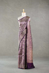 A purple Banarasi silk saree draped on a mannequin against a gray background