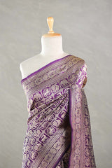 A purple Banarasi silk saree draped on a mannequin against a gray background