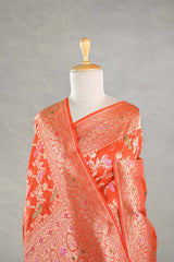 Orange saree with intricate patterns on a mannequin against a gray background