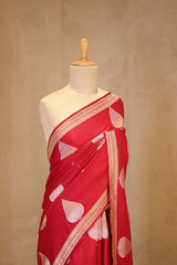 A red Banarasi silk saree with silver-gold zari motifs on dummy