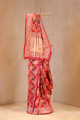 Saree with a red and beige pattern on a wooden stand against a beige background