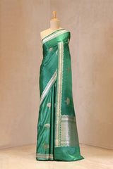 Green saree with white border on a mannequin against a beige background