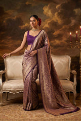 Woman in a traditional purple saree sitting on an ornate chair with a dramatic background