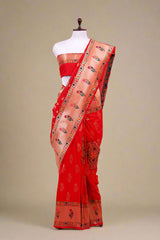A red Paithani woven silk saree displayed on a mannequin with gold zari woven floral buta and a paithani woven border and pallu, including a matching woven blouse piece.