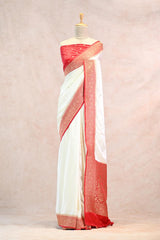 White saree with red border on a mannequin against a neutral background