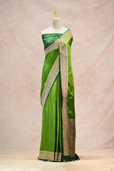 Green saree with gold border on a mannequin against a beige background