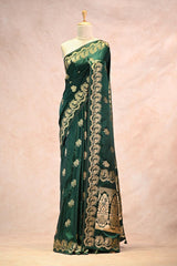 Green saree with gold embroidery on a mannequin against a beige background