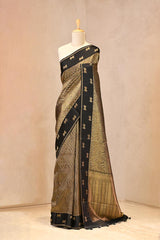 Close up of Black Semi Viscose Silk Saree showing gold zari wave brocade pattern on the body and satin border with Pichwai motifs.