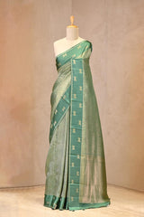 Close up of Rama Green Semi Viscose Silk Saree showing gold zari wave brocade pattern on the body and satin border with Pichwai motifs.