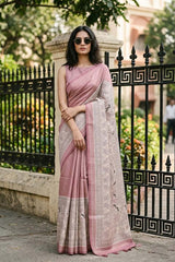 Women in of Nude Pink Semi-Silk Saree showing water gold zari butis on the body and a Madhubani printed border featuring folk-art figures.