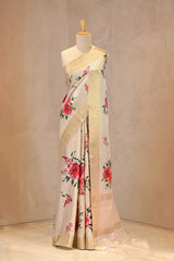 Close up of Off-White Semi Tussar Saree showing gold zari woven checkered pattern on the body and multicolor digital floral prints.