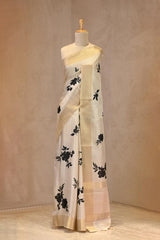 Close up of Off-White Semi Tussar Saree showing gold zari woven checkered pattern on the body and digital floral prints.