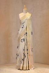 Close up of Off-White Semi Tussar Saree showing gold zari woven checkered pattern on the body and floral prints.