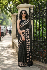 Women in Black Semi-Tussar Silk Saree showing gold zari woven checkered pattern on the body and applique work on the border.