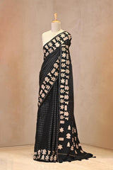 Close up of Black Semi-Tussar Silk Saree showing gold zari woven checkered pattern on the body and applique work on the border.