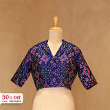 Blue patterned blouse on a mannequin with a beige background and 50% off label.