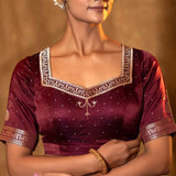 A close-up image of a woman wearing a brown satin silk blouse with gold zari accents, designed for a bridal wedding day