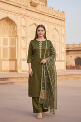 A woman in a green silk salwar suit set outfit standing in front of an architectural structure.