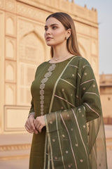 A woman in a green silk salwar suit set outfit standing in front of an architectural structure.