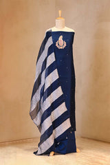 Navy blue and gray striped garment with a brooch on a mannequin against a beige background