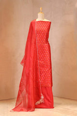 Red traditional outfit with a sheer dupatta on a mannequin against a beige background
