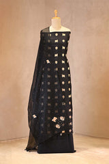 Black dress with gold embroidery on a mannequin against a beige background