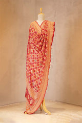 Red and orange saree on a mannequin against a beige background