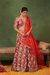 Multicolor dupion silk lehenga with abstract print, gold zari buti detailing, lace border, matching blouse, and red organza silk dupatta