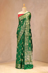 Shop elegant green Chiniya silk saree with water gold zari Pichwai Kamdhenu motifs, lotus border, and contrast red blouse. Perfect for weddings and festive wear.