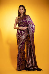 A woman posing in a wine and black Banarasi saree with geometric zari-woven motifs and a buta design, on a yellow background.